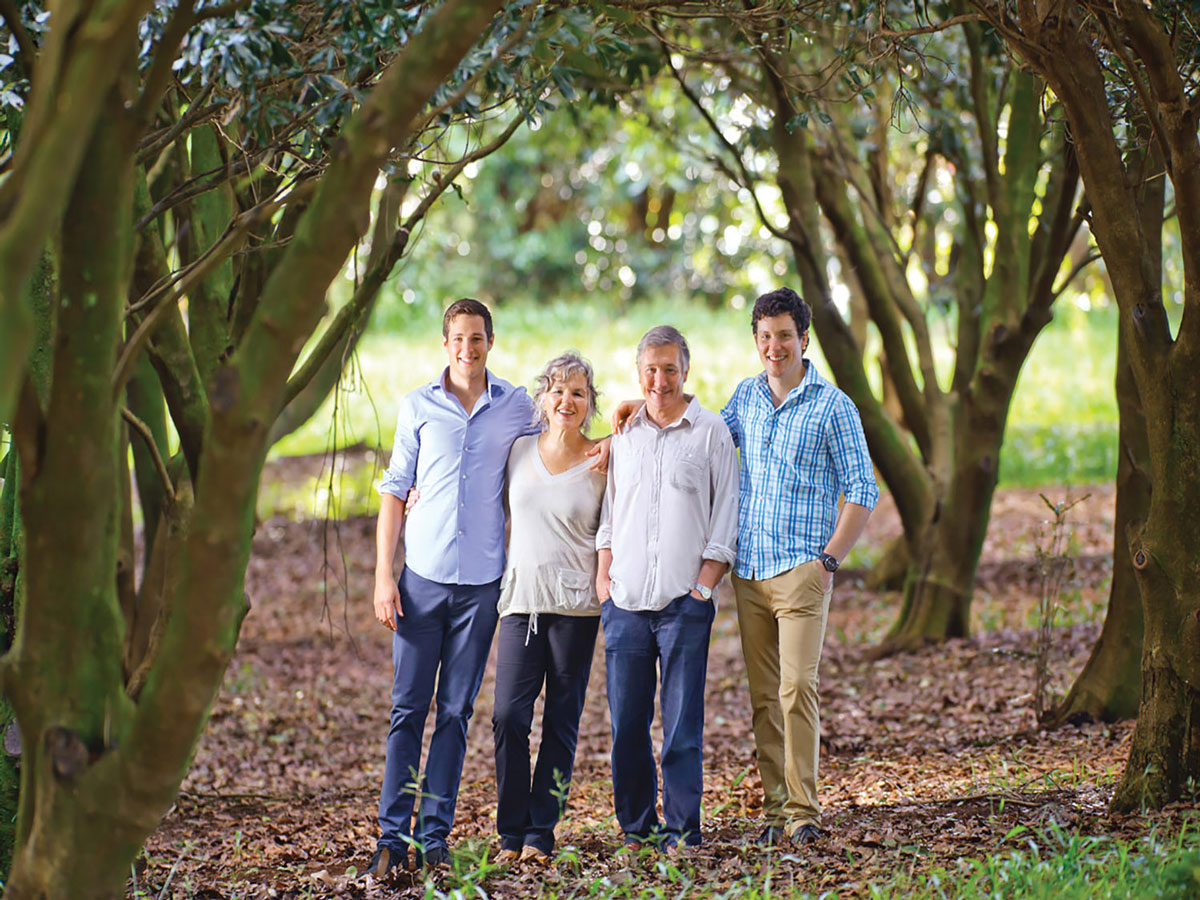 Photo of Pam and Martin Brook with their two sons all dressed in blue and white standing under the trees in their macadamia nut plantation near Byron Bay .0