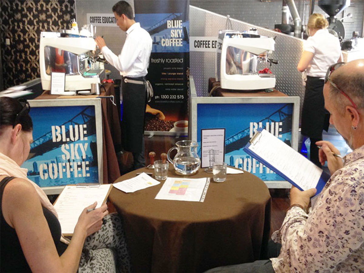 Judges, Sherrie Smith and Alex Milosevic writing comments on the scoresheets of competitors at the 2014 Brisbane Become A Barista competition at Blue Sky Coffee in Fortitude Valley