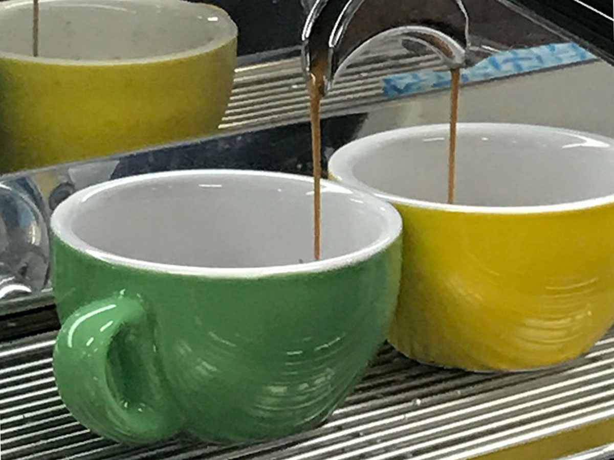 Two espressos being extracted in yellow and green cups at the 2017 Become A Barista schools barista competition at Extraction Artisan Coffee