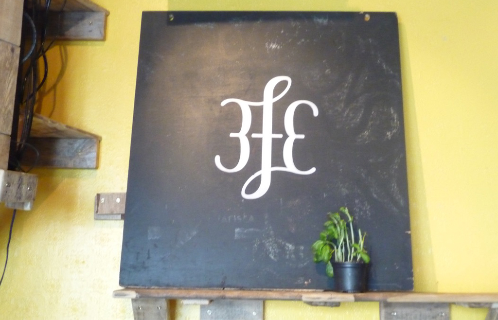 Blackboard sign with stylised 3FE logo in white - at Colin Harmon's cafe in Dublin, Ireland