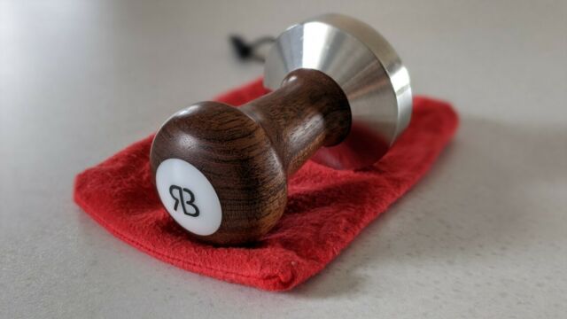 wooden handled tamper with the letters RB lying on a red pouch
