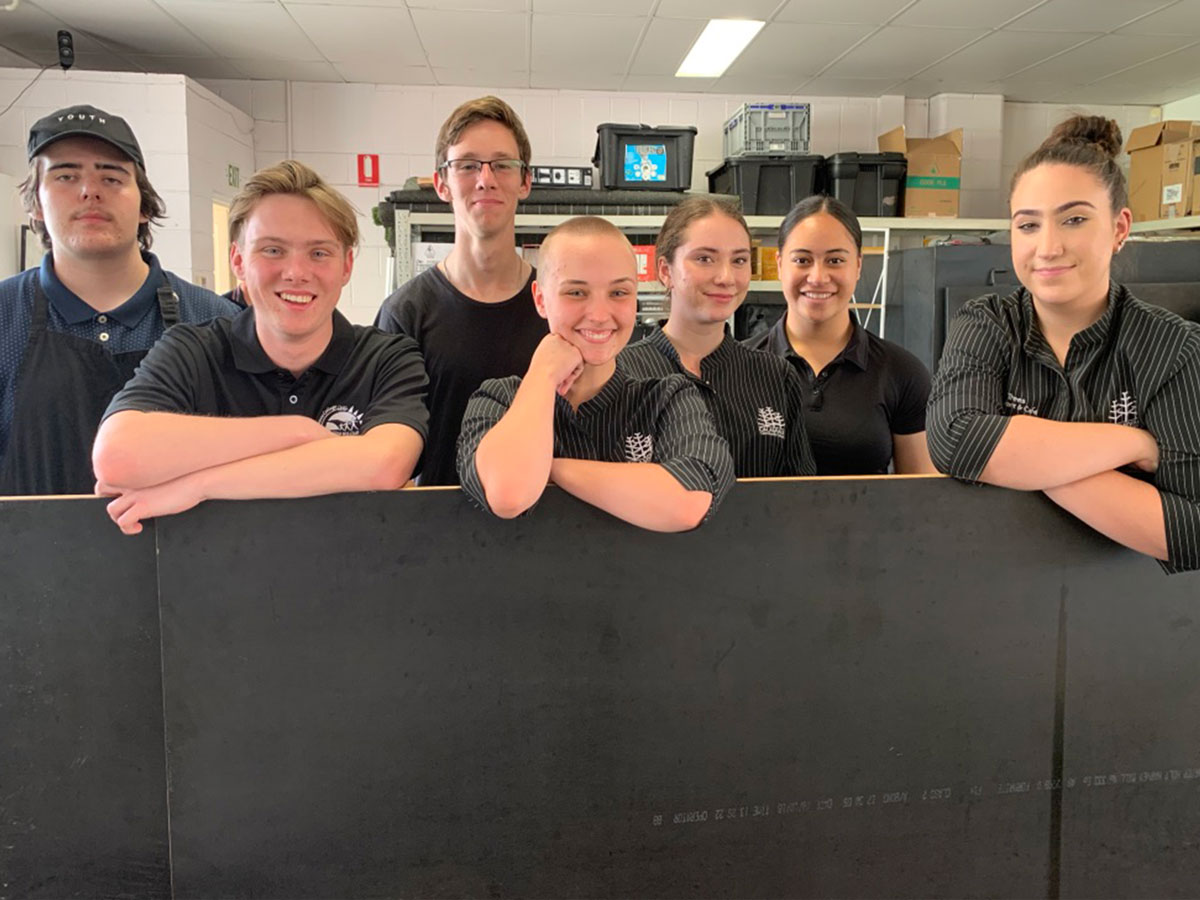 Group of seven budding trainee baristas all dressed in black and smiling at the 2019 Become a Barista competition held at Tim Adams Specialty Coffee